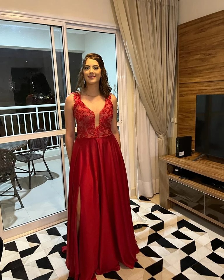 Cliente com vestido de festa longo vermelho, com renda no corpete e fenda na saia